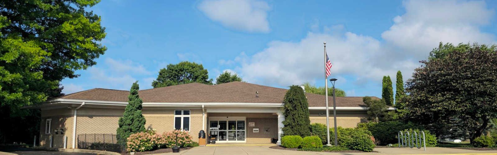 Sunny Day at the library building with an American Flag - Lush Greenery and Blue Sky Background