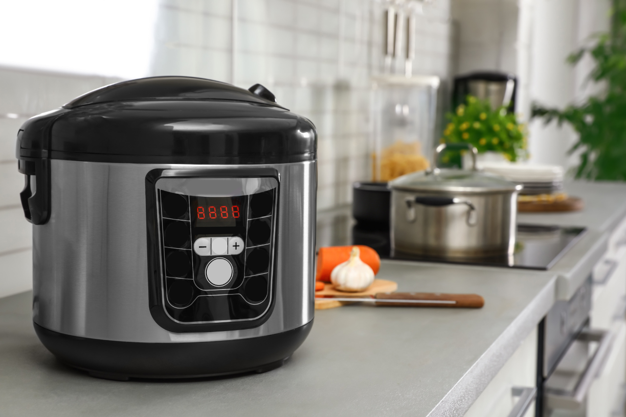 Modern multi-cooker with digital display on kitchen countertop with stainless steel cookware in the background. Convenient appliance for quick and healthy cooking.